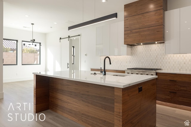 2752 S 3930 W, Hurricane, UT 84737 - kitchen featuring decorative light fixtures, white cabinets, decorative backsplash, a kitchen island with sink, and a barn door