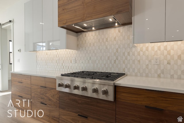 2752 S 3930 W, Hurricane, UT 84737 - kitchen featuring premium range hood, white cabinetry, stainless steel gas stovetop, a barn door, and backsplash