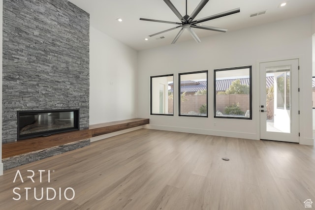 2752 S 3930 W, Hurricane, UT 84737 - unfurnished living room with ceiling fan, a stone fireplace, light hardwood / wood-style flooring, and a high ceiling