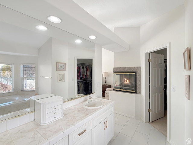 bathroom featuring tiled tub, vanity, a multi sided fireplace, and tile patterned floors