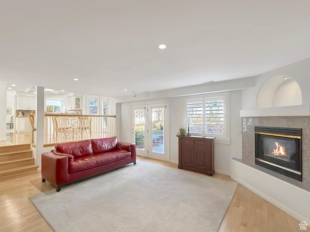 living room with a high end fireplace and light hardwood / wood-style flooring