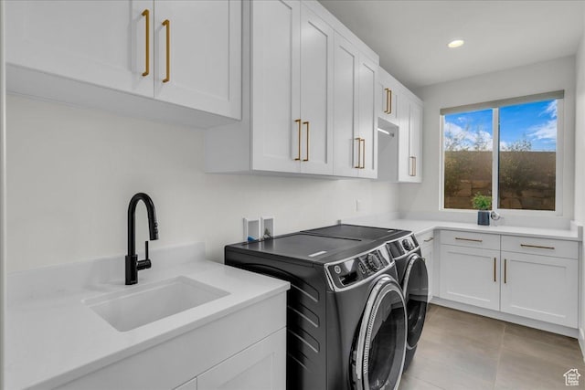 washroom with cabinets, sink, light tile patterned floors, and washer and clothes dryer
