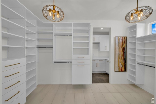 spacious closet with a notable chandelier and light tile patterned flooring