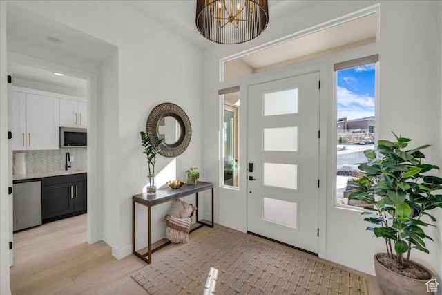 entrance foyer featuring sink, a chandelier, and light hardwood / wood-style floors