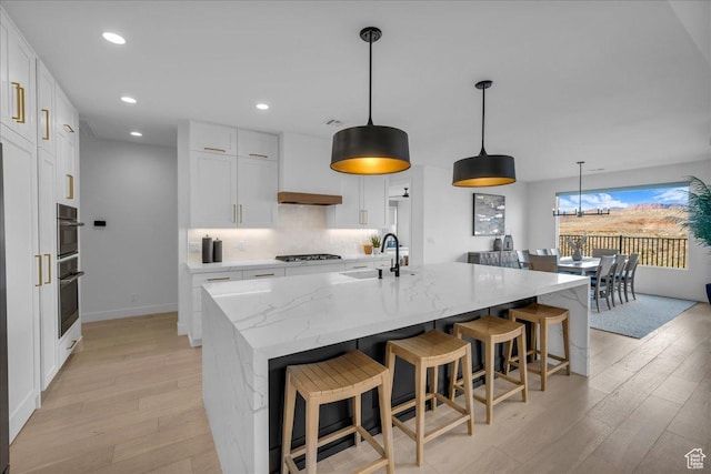 kitchen with white cabinetry, a large island, hanging light fixtures, and gas stovetop