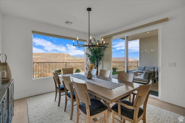 dining space featuring a mountain view, light hardwood / wood-style floors, and a notable chandelier