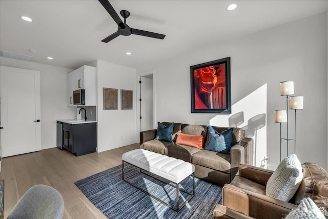living room with ceiling fan, sink, and light wood-type flooring