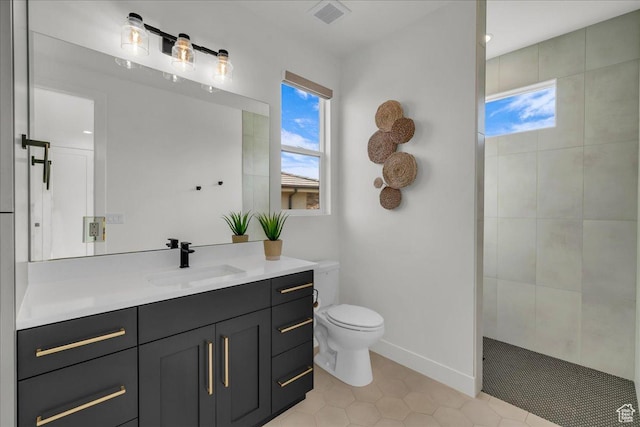 bathroom featuring tiled shower, vanity, and toilet