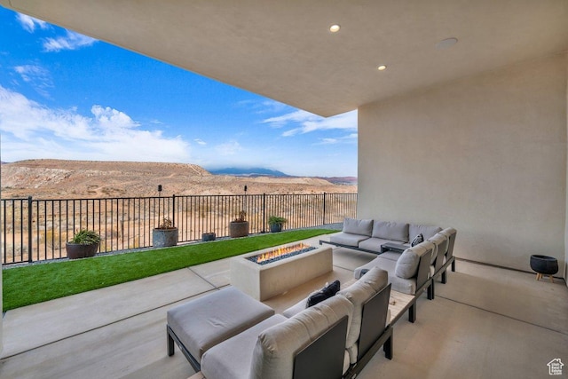 view of patio with a mountain view and an outdoor living space with a fire pit
