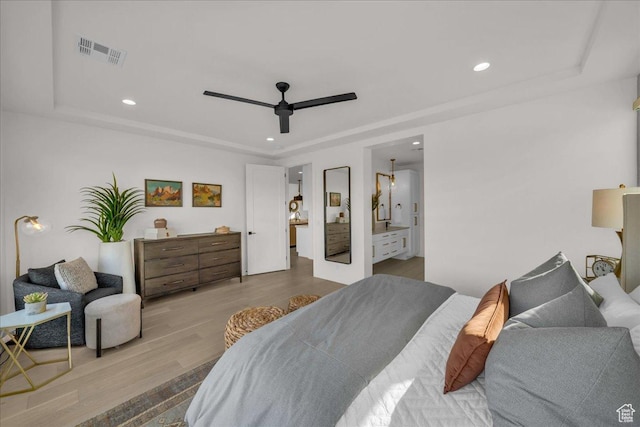 bedroom featuring a raised ceiling, ceiling fan, and light wood-type flooring