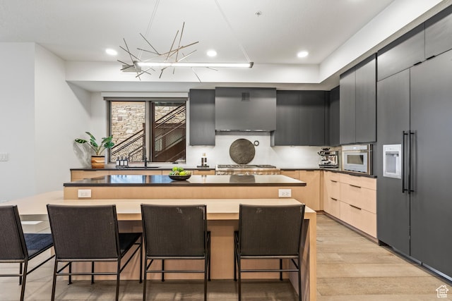1271 Lowell Ave Unit B202, Park City, UT 84060 - kitchen with a breakfast bar, wall chimney exhaust hood, a center island, and light hardwood / wood-style floors