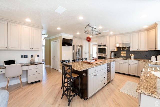 6658 S Caracol Cv, Cottonwood Heights, UT 84121 - kitchen featuring appliances with stainless steel finishes, a kitchen bar, a kitchen island, light wood-type flooring, and recessed lighting