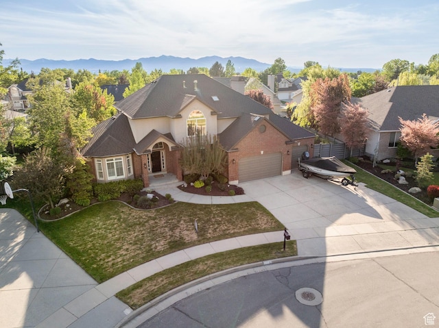 6658 S Caracol Cv, Cottonwood Heights, UT 84121 - view of front of home featuring concrete driveway, an attached garage, brick siding, a front lawn, and a mountain view