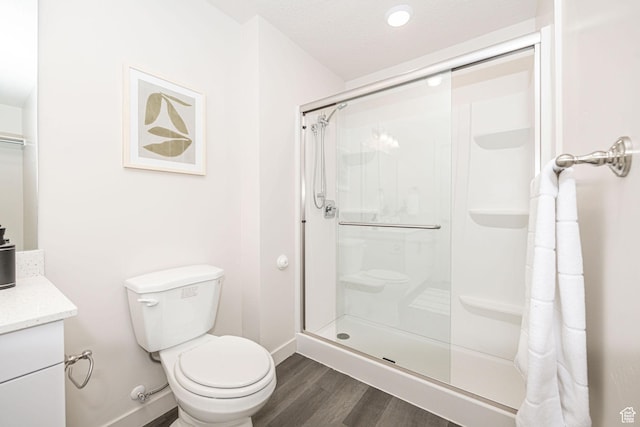 full bath featuring a shower stall, toilet, vanity, and wood finished floors