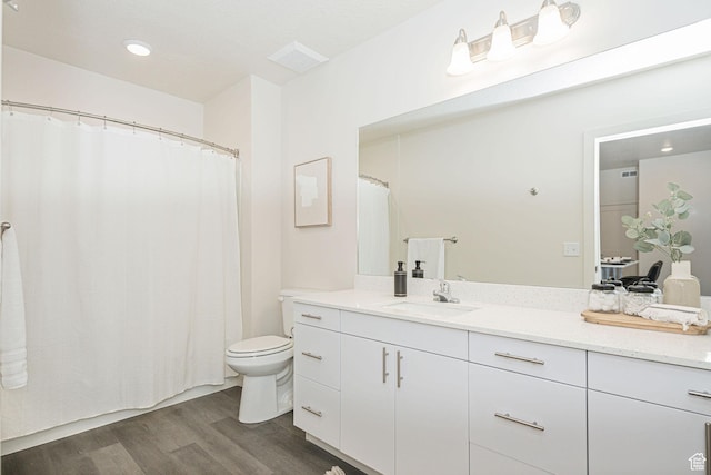 bathroom featuring vanity, toilet, wood finished floors, and visible vents