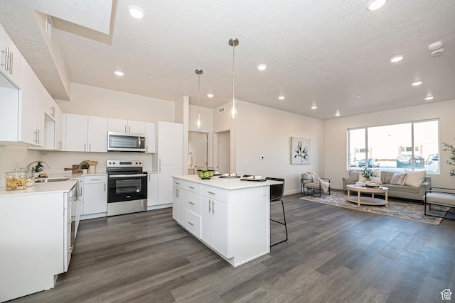 kitchen with a breakfast bar, a sink, a kitchen island, stainless steel appliances, and dark wood-style flooring
