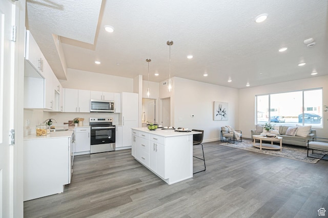 kitchen featuring light wood finished floors, a center island, a breakfast bar area, appliances with stainless steel finishes, and a sink