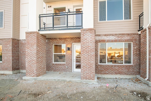 entrance to property featuring brick siding and a balcony