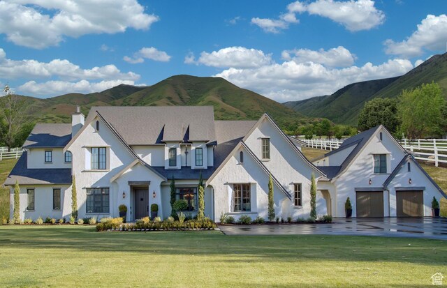 view of front of property with fence, a chimney, a garage, a front yard, and a mountain view