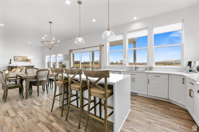 3932 W 2875 N, Plain City, UT 84404 - kitchen with recessed lighting, light wood-style floors, a sink, light countertops, and a breakfast bar area