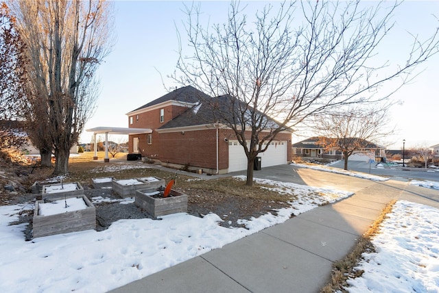 434 S Cardon Ridge Dr, Smithfield, UT 84335 - view of snowy exterior featuring driveway, brick siding, and a garage