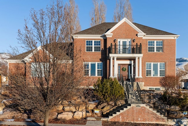434 S Cardon Ridge Dr, Smithfield, UT 84335 - colonial home featuring a balcony, brick siding, a shingled roof, and stairway