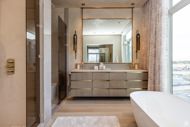 1920 E Rodeo Walk Dr Unit 516, Holladay, UT 84117 - bathroom featuring wood finished floors, a soaking tub, double vanity, and toilet