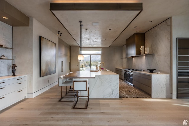 1920 E Rodeo Walk Dr Unit 516, Holladay, UT 84117 - kitchen featuring range with two ovens, modern cabinets, light wood finished floors, light countertops, and an island with sink