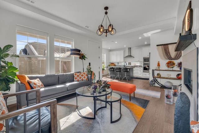 living room featuring hardwood / wood-style flooring, sink, and an inviting chandelier