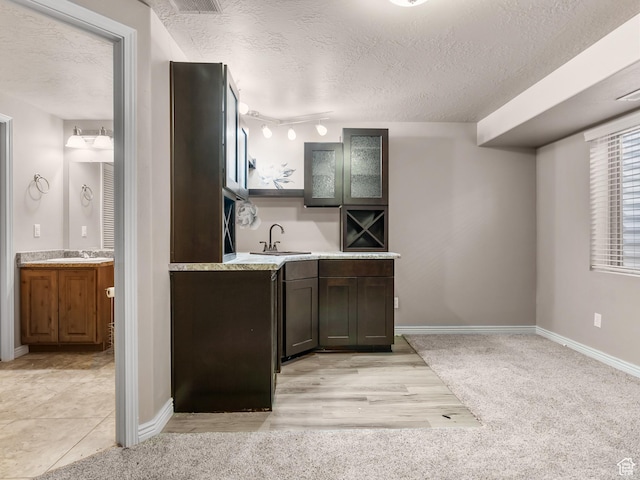 kitchen featuring dark brown cabinetry, sink, and a textured ceiling