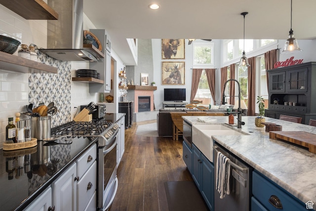 424 E Secret Cove Ct, Moab, UT 84532 - kitchen with blue cabinets, appliances with stainless steel finishes, open shelves, a sink, and wall chimney exhaust hood