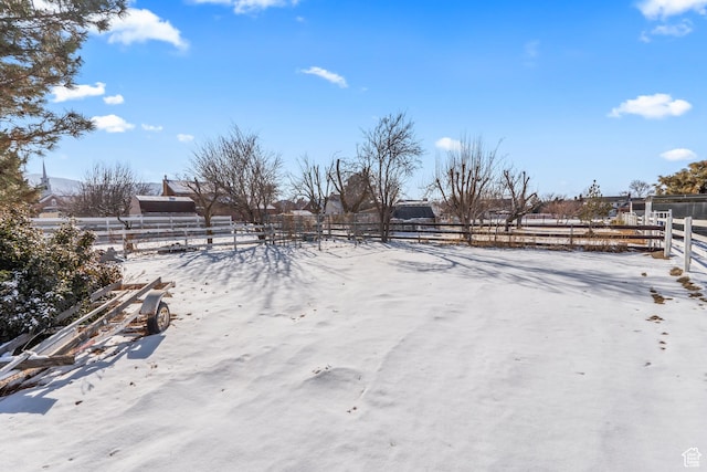 yard covered in snow with a rural view