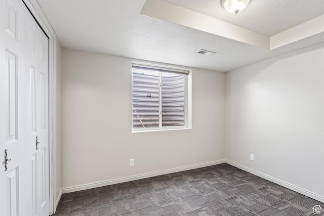 interior space with a closet, a textured ceiling, and dark colored carpet