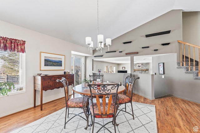 dining space featuring lofted ceiling, light hardwood / wood-style floors, and a notable chandelier