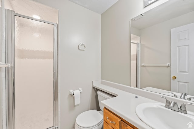 bathroom featuring vanity, a shower with door, and toilet