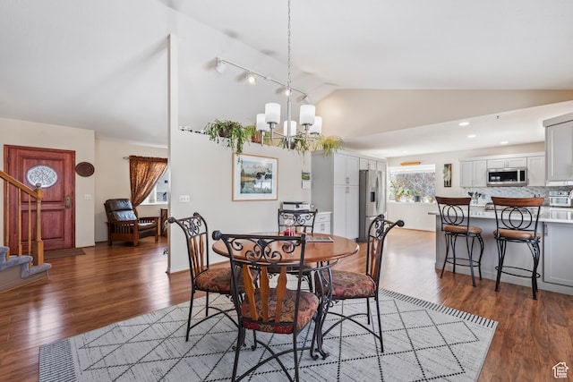 dining space featuring an inviting chandelier, dark wood-type flooring, and vaulted ceiling