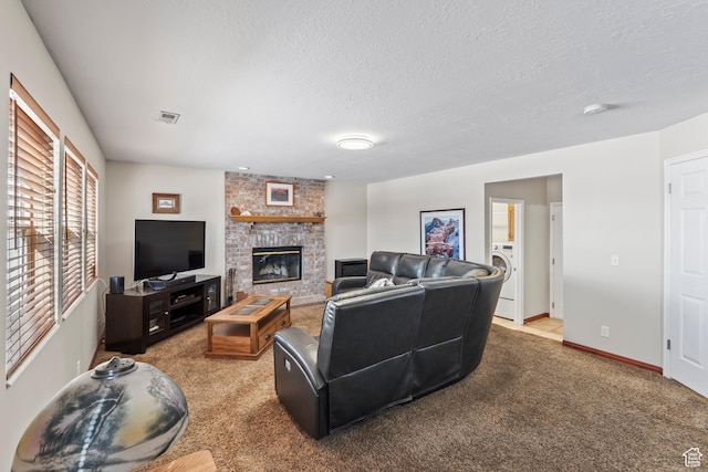carpeted living room with a brick fireplace, washer / dryer, and a textured ceiling