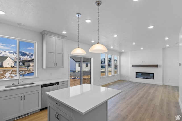 kitchen featuring sink, tasteful backsplash, decorative light fixtures, stainless steel dishwasher, and gray cabinets