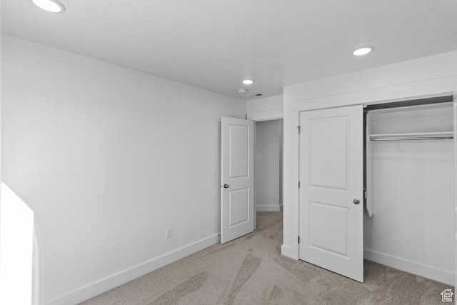 unfurnished bedroom featuring light carpet and a closet