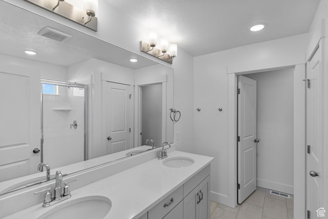 bathroom featuring a shower with door, vanity, tile patterned floors, and a textured ceiling