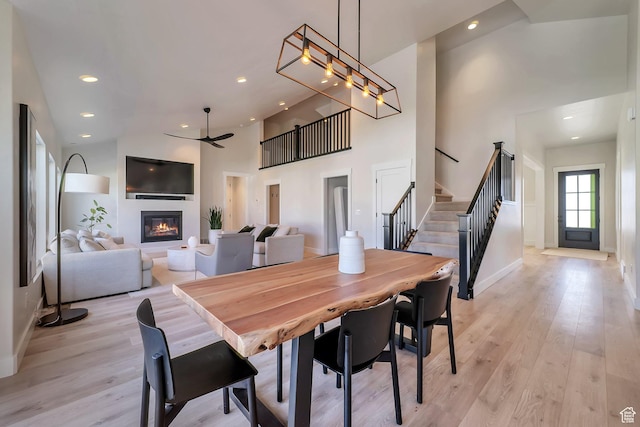 1521 E Thorpe Dr, Eagle Mountain, UT 84005 - dining room with high vaulted ceiling, light wood-style flooring, a glass covered fireplace, ceiling fan, and stairs