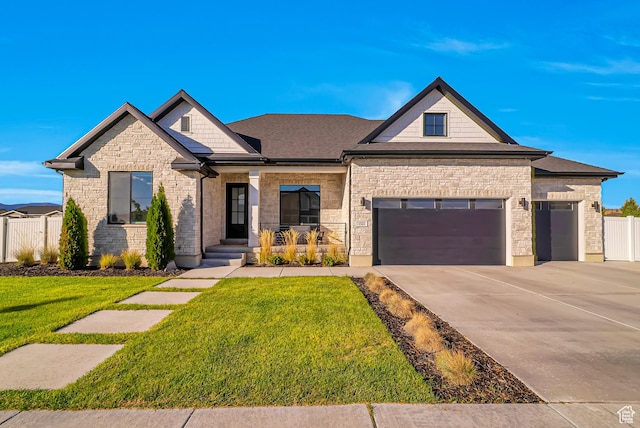 view of front of home featuring stone siding, an attached garage, a front lawn, and fence