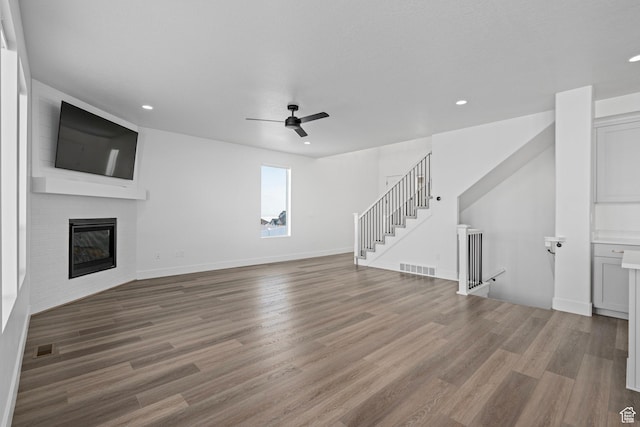 1504 S Lukas Ln, Saratoga Springs, UT 84045 - unfurnished living room with wood-type flooring, a large fireplace, and ceiling fan