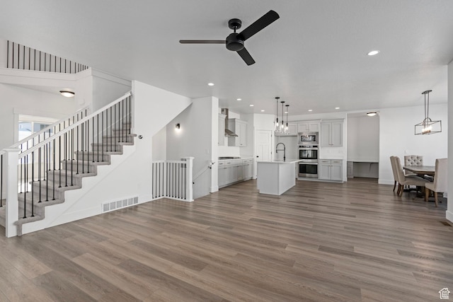 unfurnished living room featuring sink, ceiling fan with notable chandelier, and dark hardwood / wood-style flooring