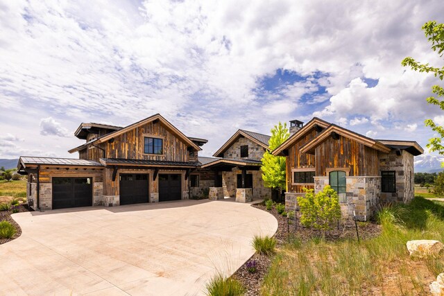 149 N Haystack Mountain Dr, Heber City, UT 84032 - view of front of house featuring stone siding, driveway, a standing seam roof, an attached garage, and a chimney