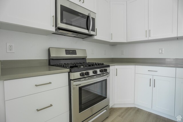 kitchen featuring stainless steel appliances, white cabinetry, and light hardwood / wood-style flooring