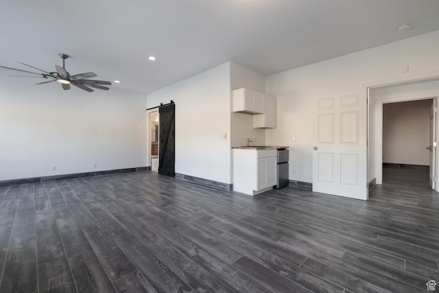 7748 W Mountain Dell Dr, Vernal, UT 84078 - unfurnished living room with dark wood-type flooring, ceiling fan, a barn door, and sink