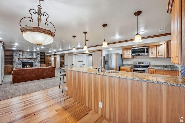12159 S Swensen Cir, Riverton, UT 84096 - kitchen with stainless steel appliances, light wood-style floors, a fireplace, light stone counters, and open floor plan