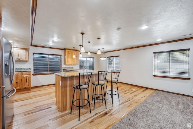12159 S Swensen Cir, Riverton, UT 84096 - kitchen featuring stainless steel refrigerator with ice dispenser, a sink, a breakfast bar, light wood-style floors, and plenty of natural light