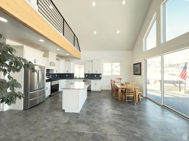 1610 N Mackinaw Way, Garden City, UT 84028 - kitchen featuring stainless steel appliances, a kitchen island, tasteful backsplash, white cabinetry, and a high ceiling
